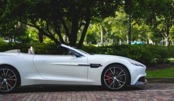 white Aston Martin convertible parked near trees